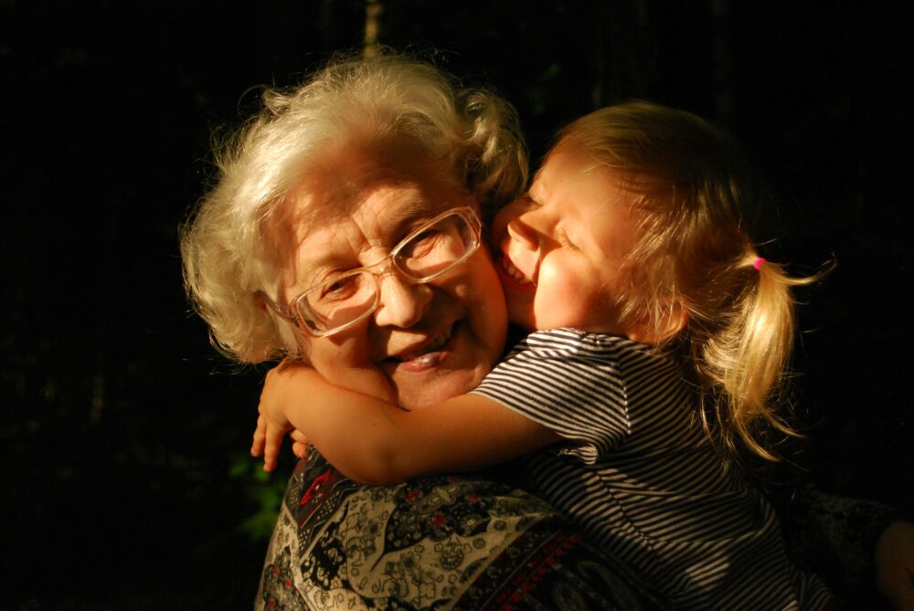 Elderly woman being embraced by her granddaughter.